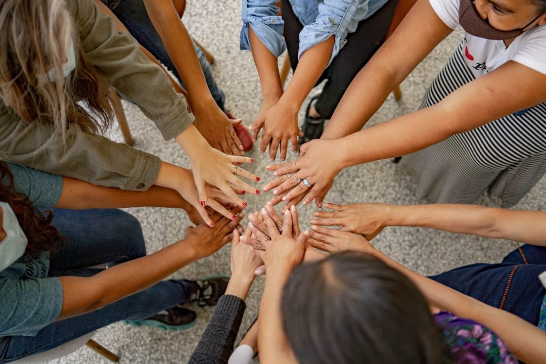 Diverse team members standing in a circle with hands together, representing community collaboration